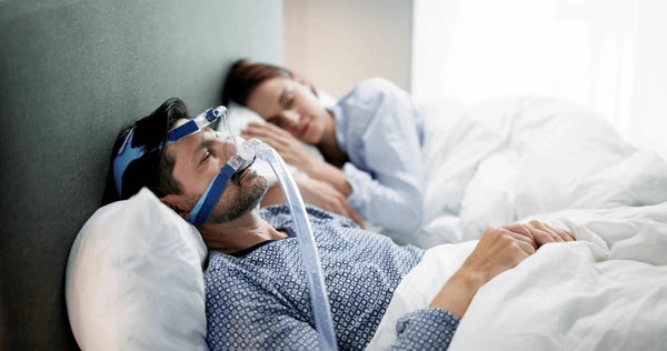 Man sleeping and using a CPAP machine in bed
